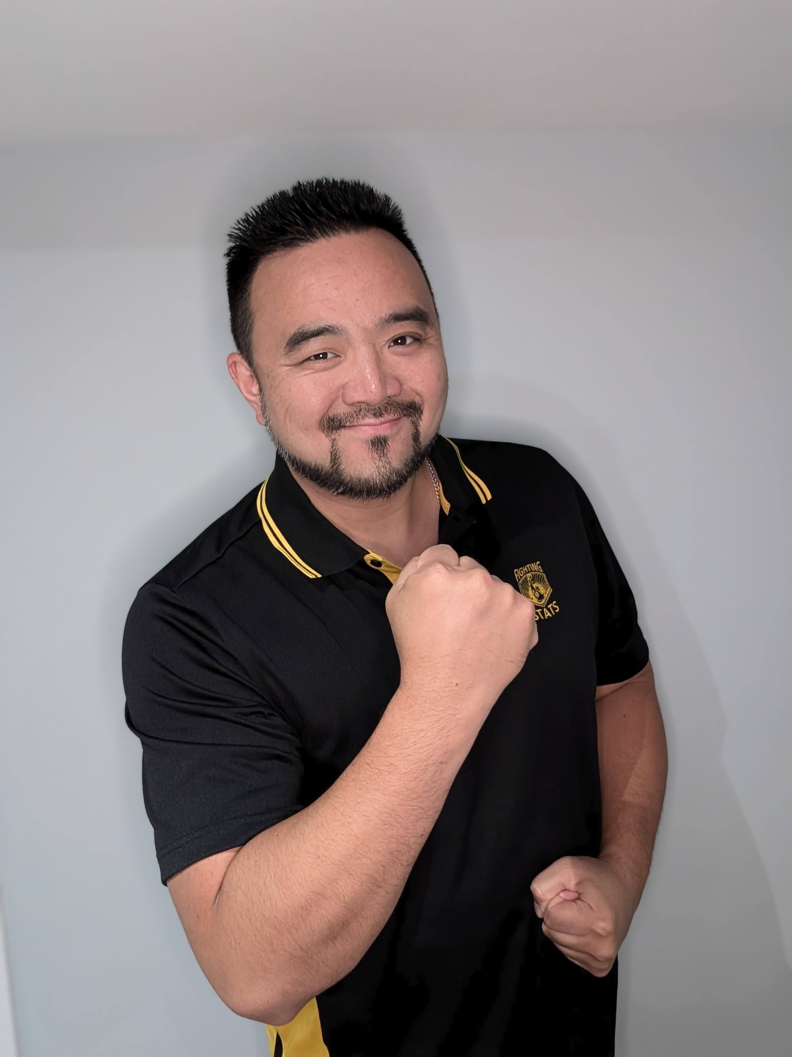 Art C smiling in a black and gold Fighting Stats polo, ready stance